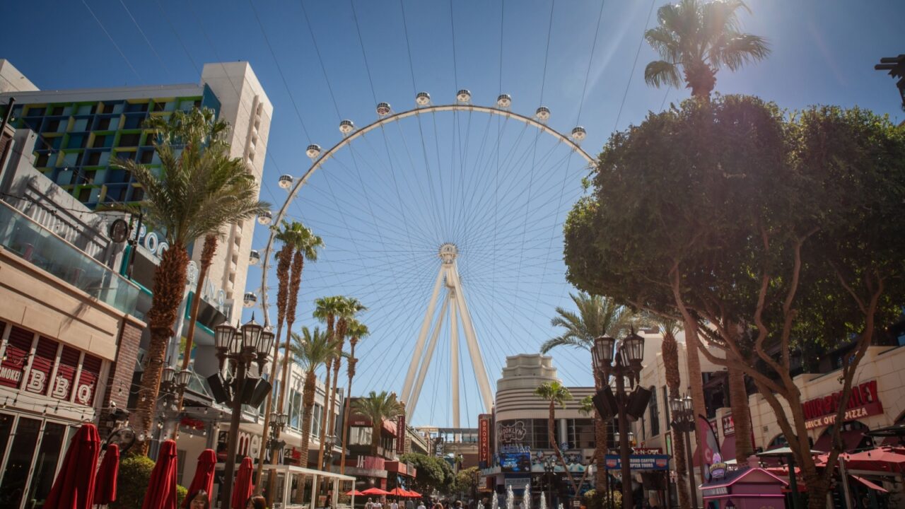LAS VEGAS, AUGUST 21, 2024: Sunlit pedestrian scene along the LINQ Promenade leading to the High Roller observation wheel on the Las Vegas Strip, Nevada, lined with palm trees, cafes, terraces.