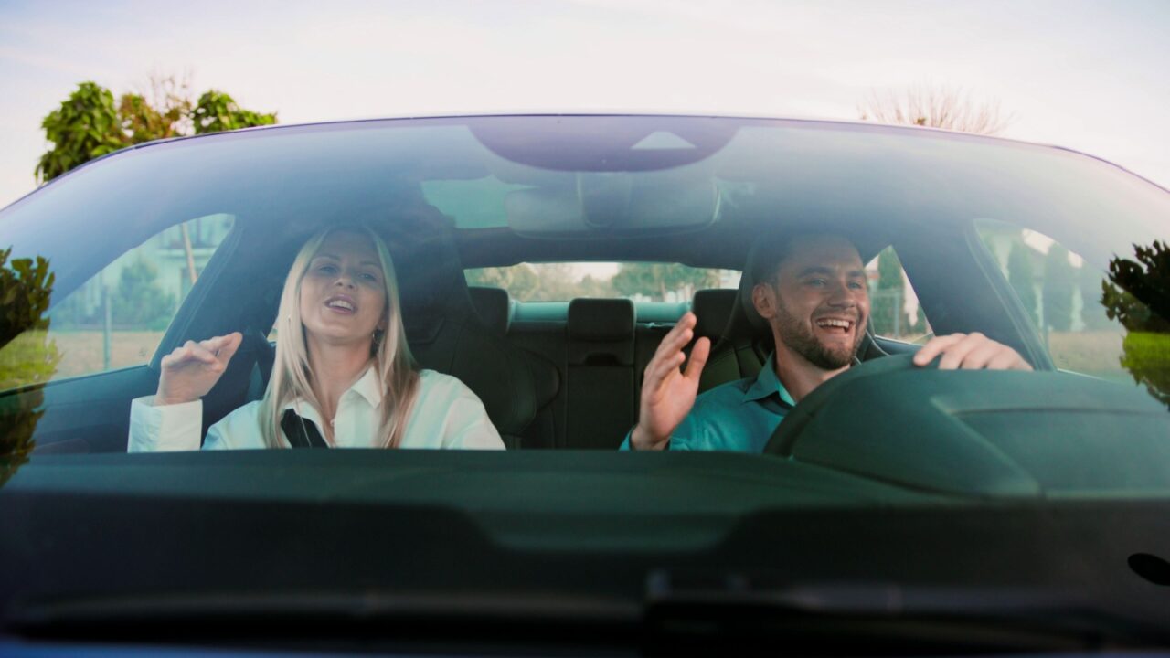 Joyful Moments Friends Singing Together While Having Fun in the Car on a Road Trip. Friends joyfully singing karaoke together in a car, relishing a scenic drive bursting with vibrant energy