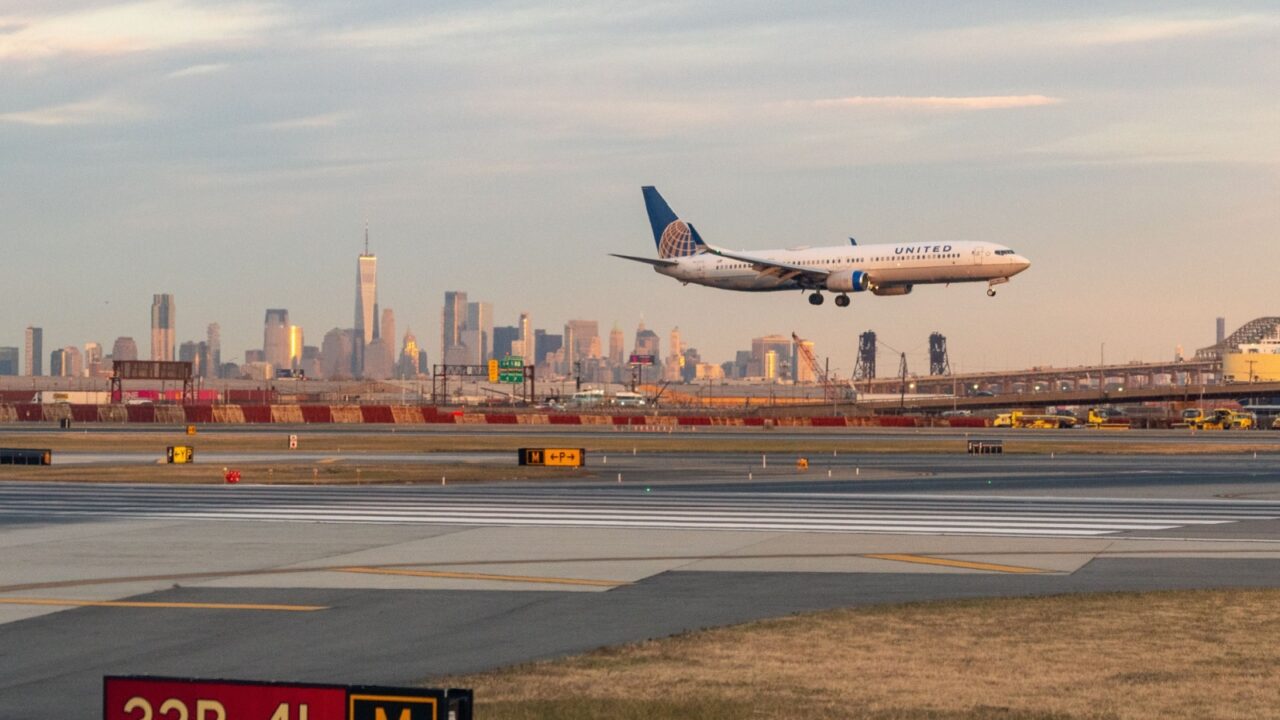 Newark Liberty Airport, Newark, New Jersey, USA - October 31, 2024 - United Airlines Jet landing at Newark Liberty Airport at golden hour with the Lower Manhattan skyline in the background