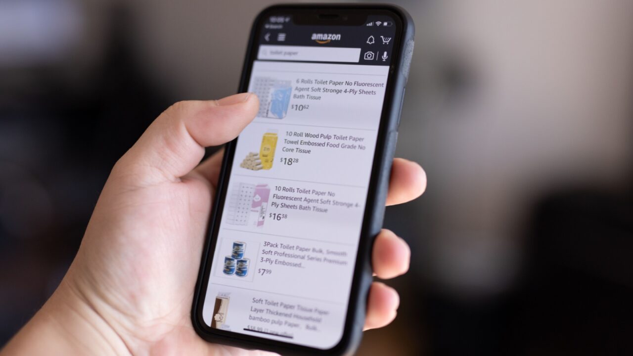 Mannheim - BW / Germany - 03.18.2020 : Close Up of Man Hold a Smartphone on the screen Amazon List with Expensive Toilet Paper