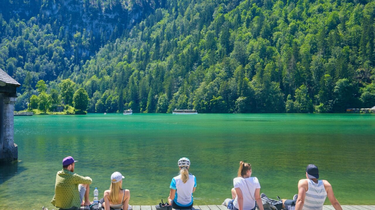 Beautiful view of Lake Königssee, with tourists dipping their feet in the water. In Bavaria, Germany.