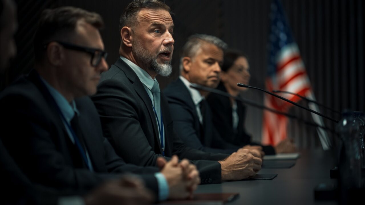 Caucasian Male Organization Representative Speaking at Economic Forum. Head Of USA Delegation Delivering Speech at International Political Summit Press Conference. Diverse Delegates Listening.