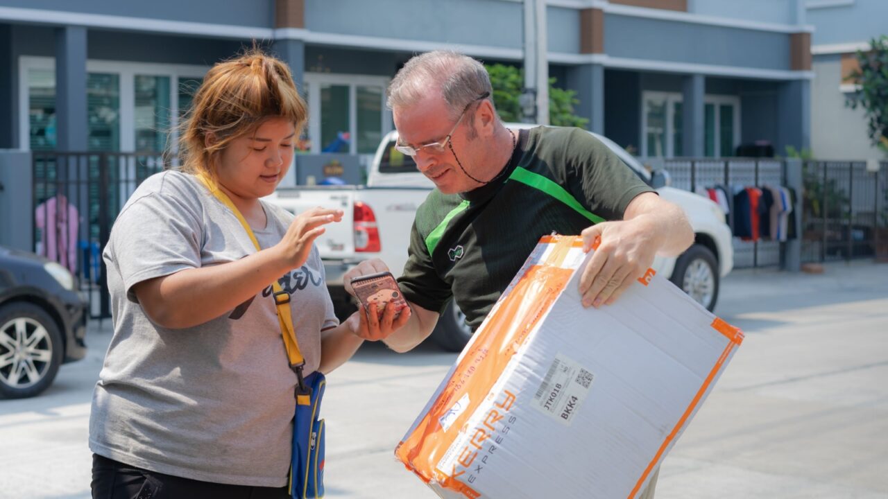 Editorial use only; a man receives a large package from a courier, taken at Pathumthani, Thailand, in January 2019.