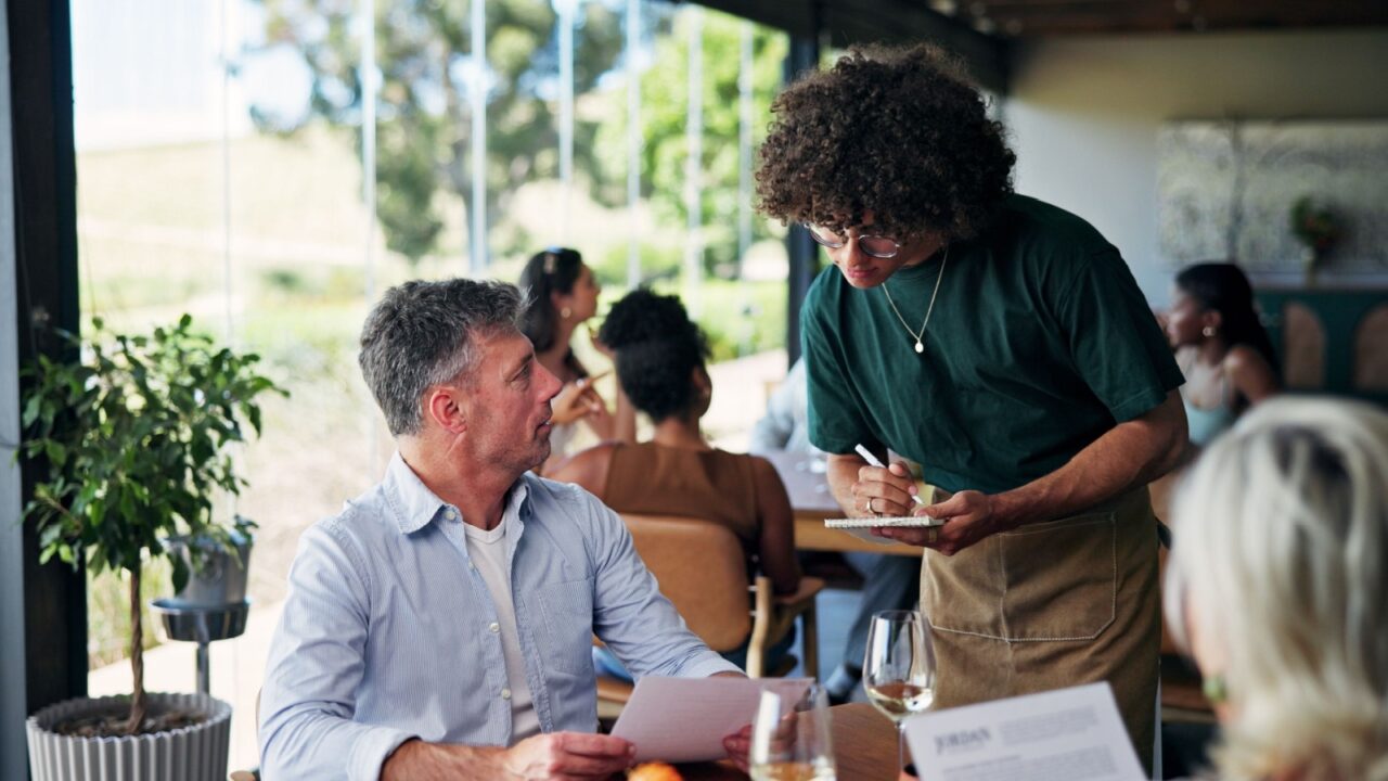 Writing, order and waiter with mature couple, menu and customer service with notepad and restaurant. Fine dining, server and person with journal for meal options, notes or info for decision in diner