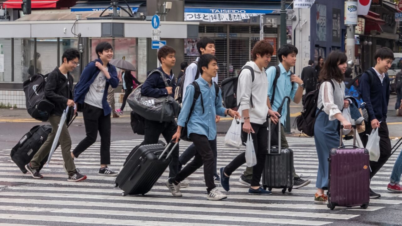 TOKYO, JAPAN - MAY 3RD, 2018. Japanese youth with luggage crossing the street in Shibuya.