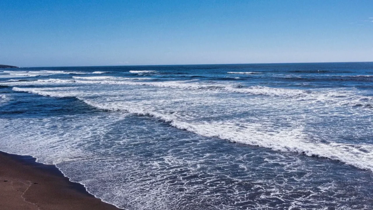 a drone shot of foamy waves crashing the goat rock