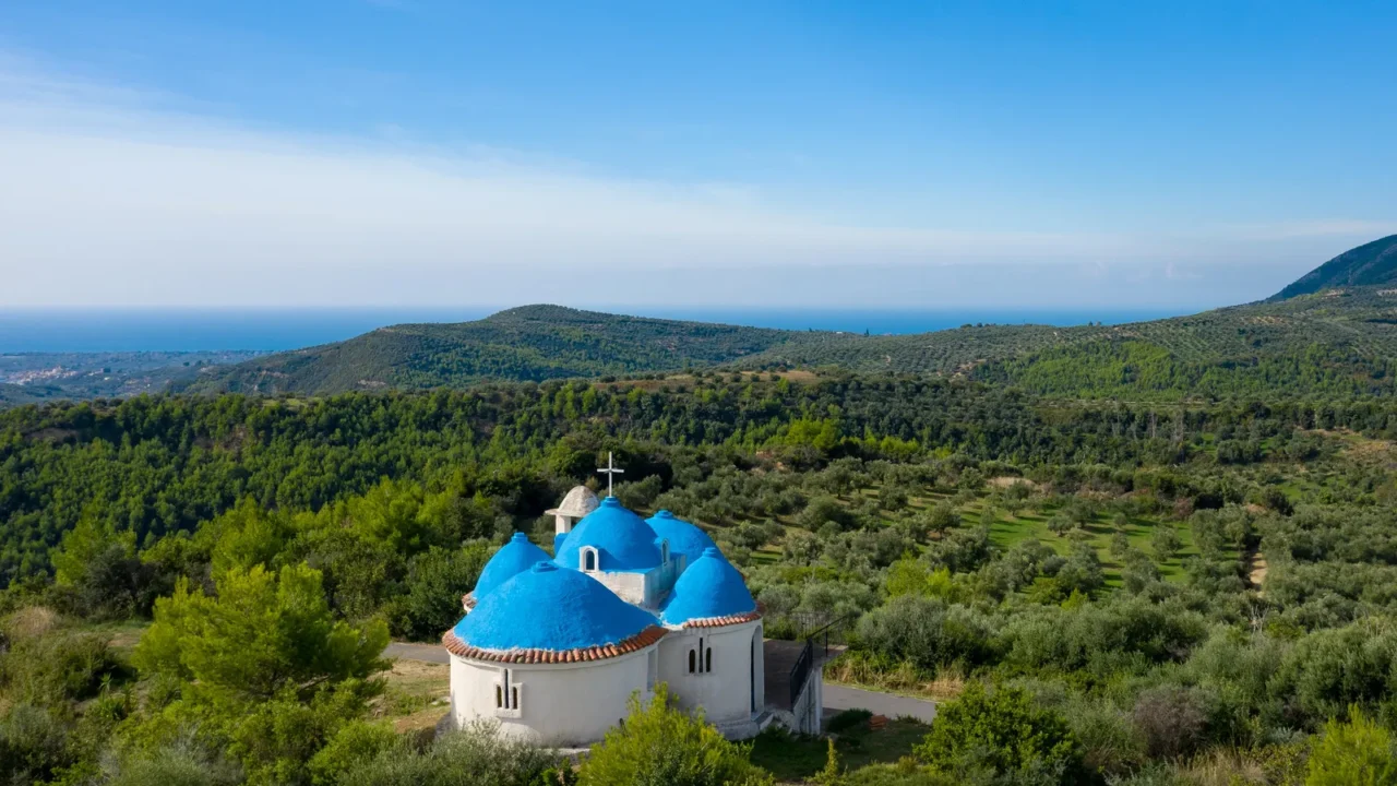 a white church with vivid blue domes stands nestled among