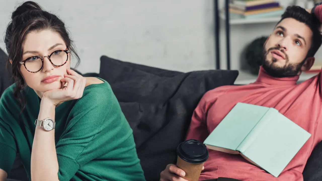bored woman in glasses holding apple and sitting near handsome