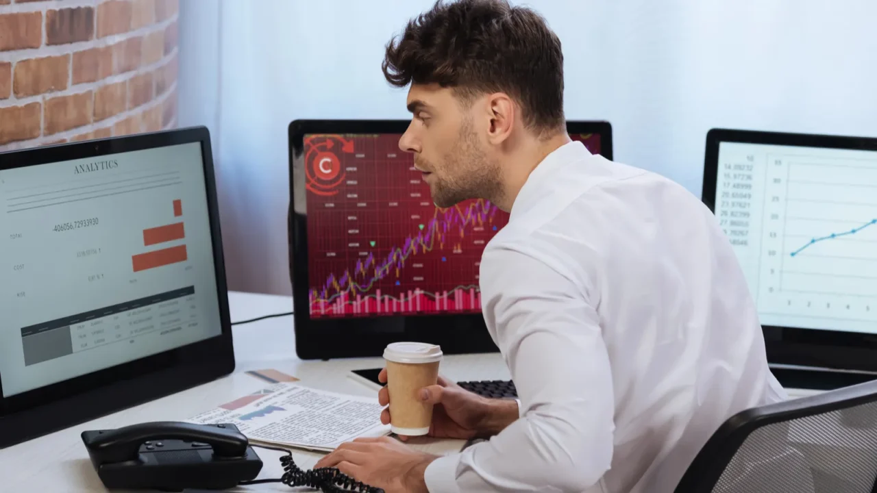 businessman holding coffee to go and analyzing finance stocks on