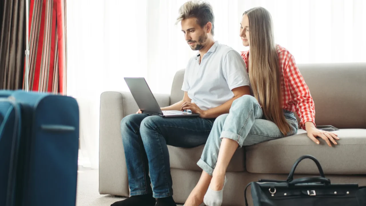 couple looks on laptop screen luggage preparation travelling or tourism