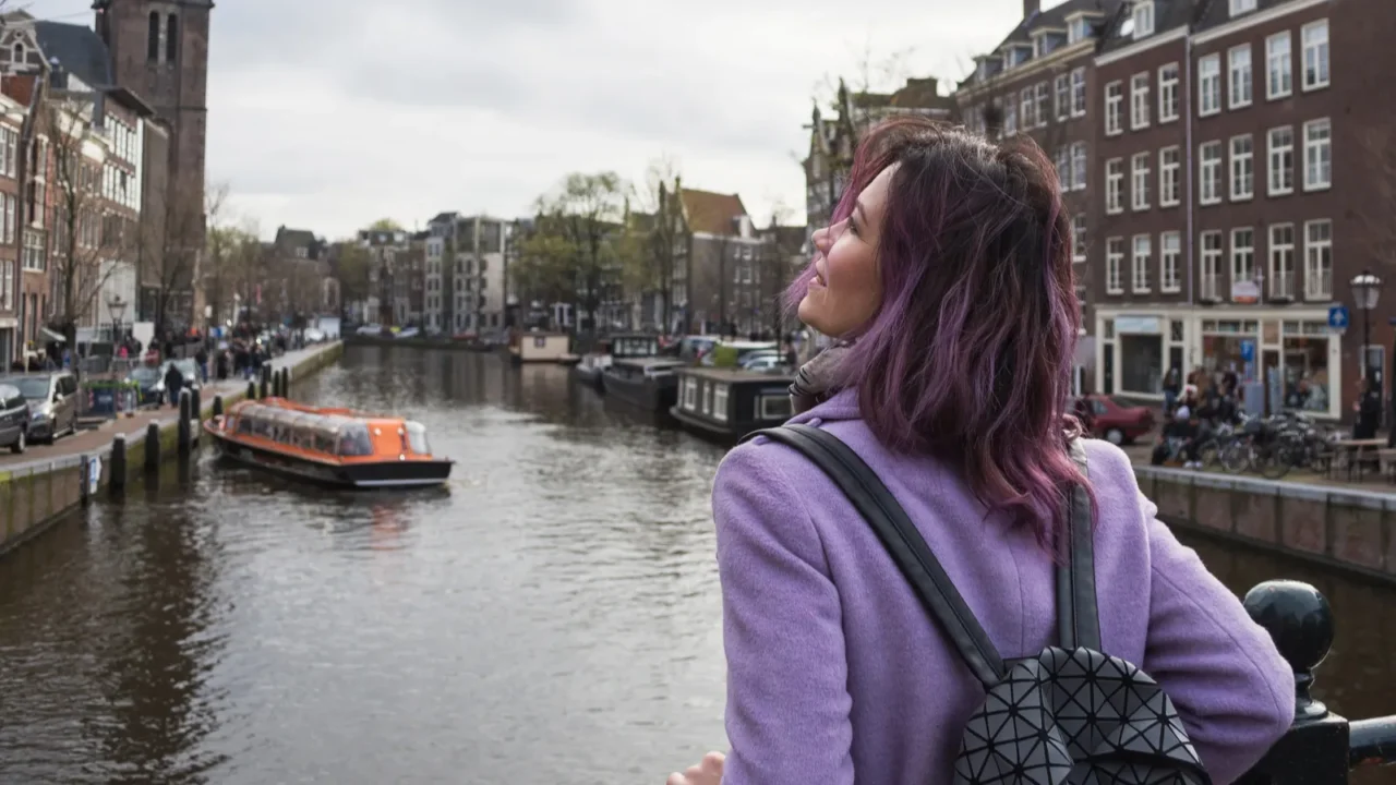 girl in the coat and backpack enjoying amsterdam city young