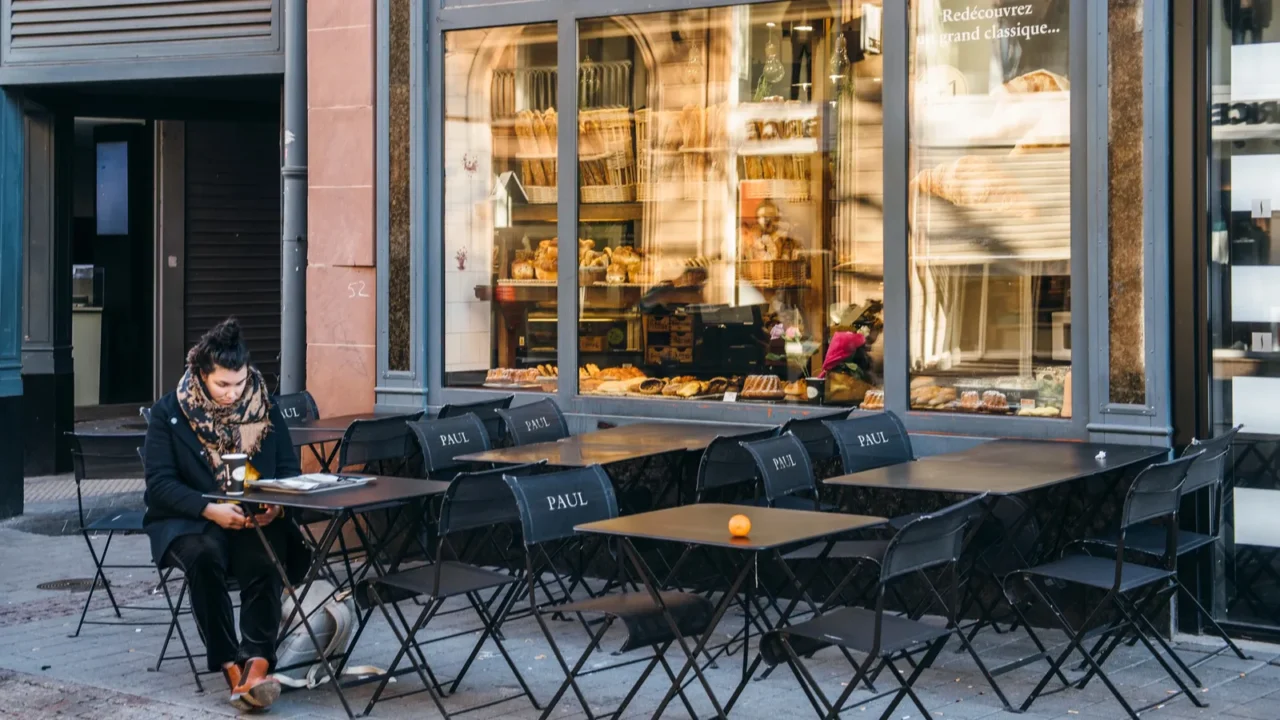 lonely woman eating croissant and drinking coffee at paul cafe