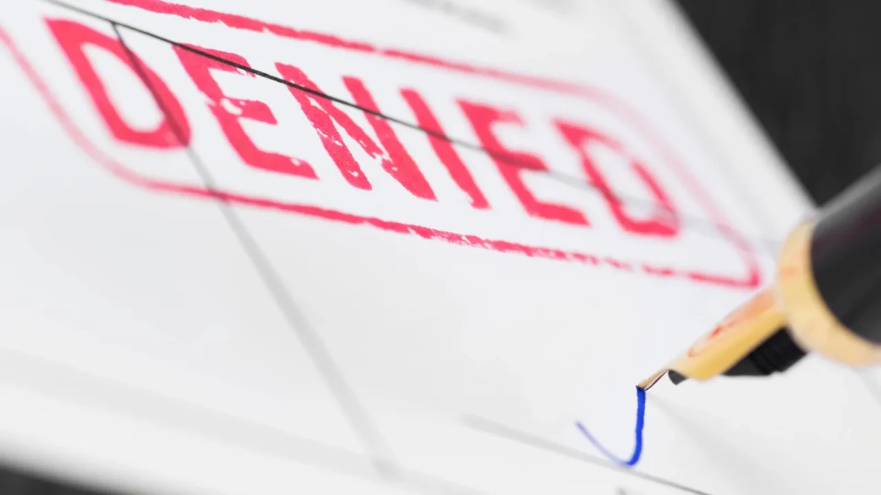 macro shot of red stamp denied and fountain pen on