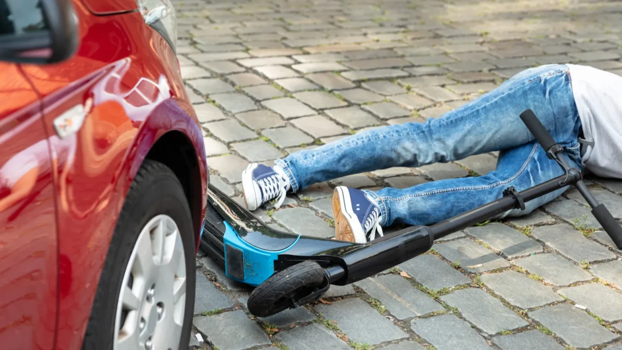 man after accident on electric scooter overrun by car