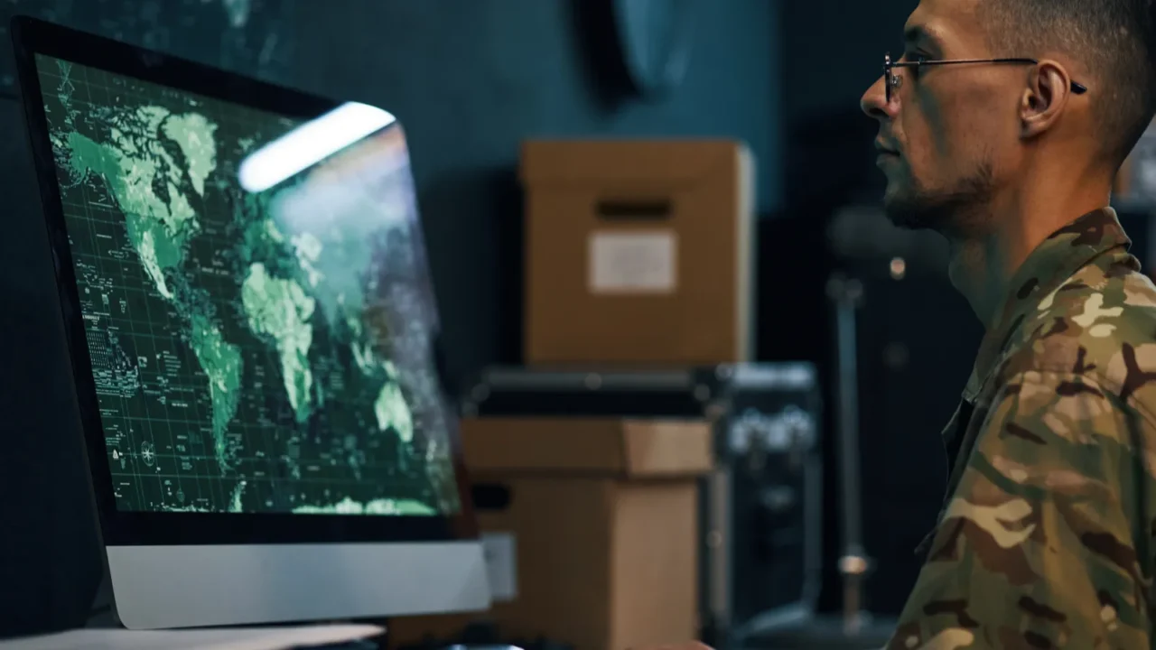 military personnel working on computer analyzing global data with maps