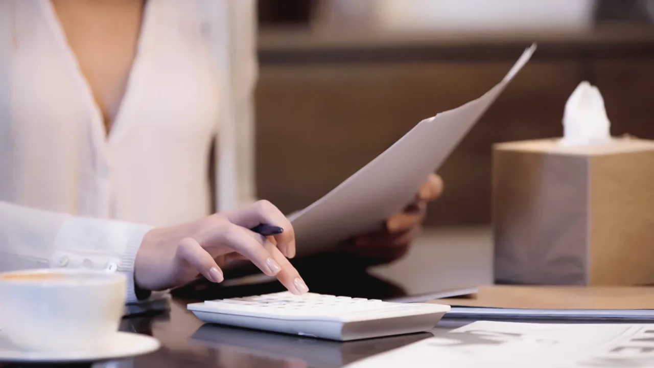 partial view of woman sitting on table with documents and