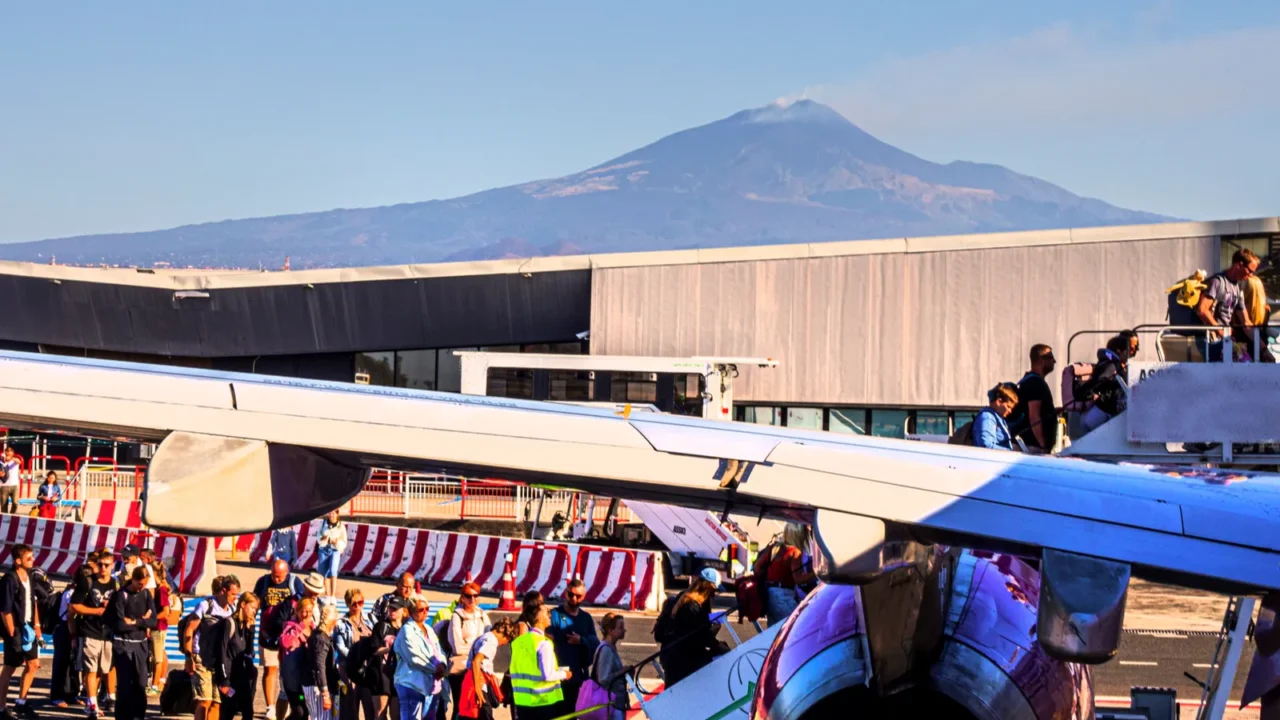 passengers board a plane at catania airport against the backdrop