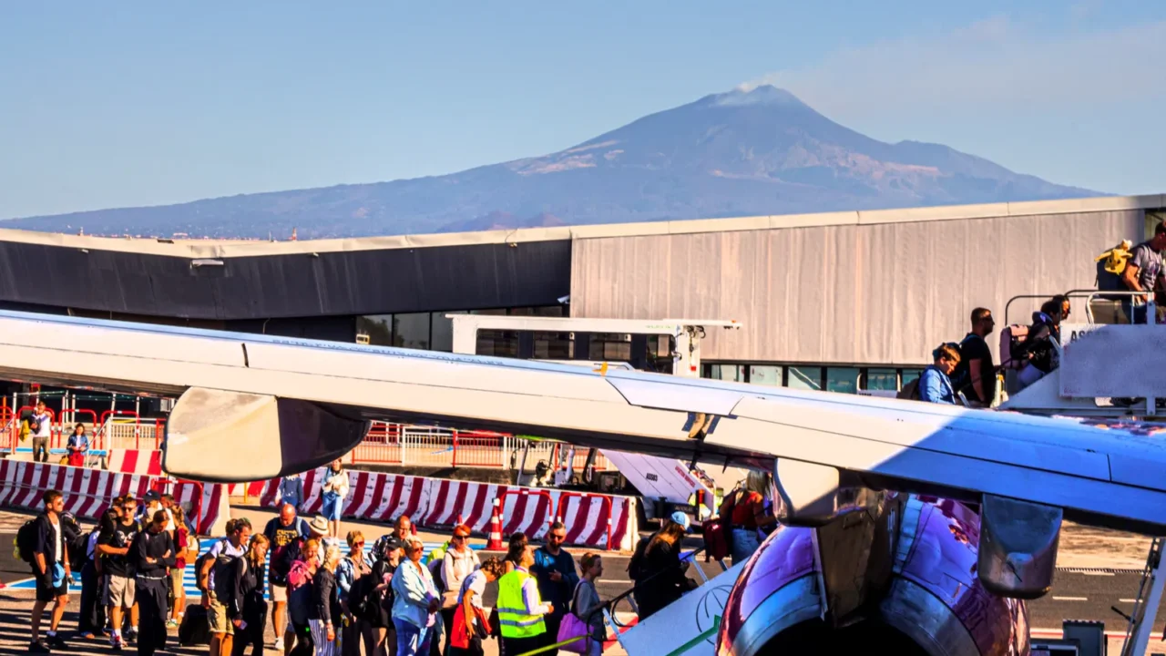 passengers board a plane at catania airport against the backdrop