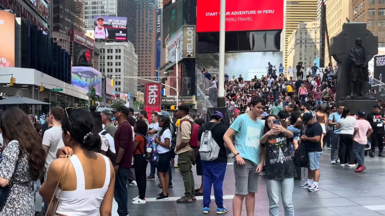 people gather across the busy streets of times square new