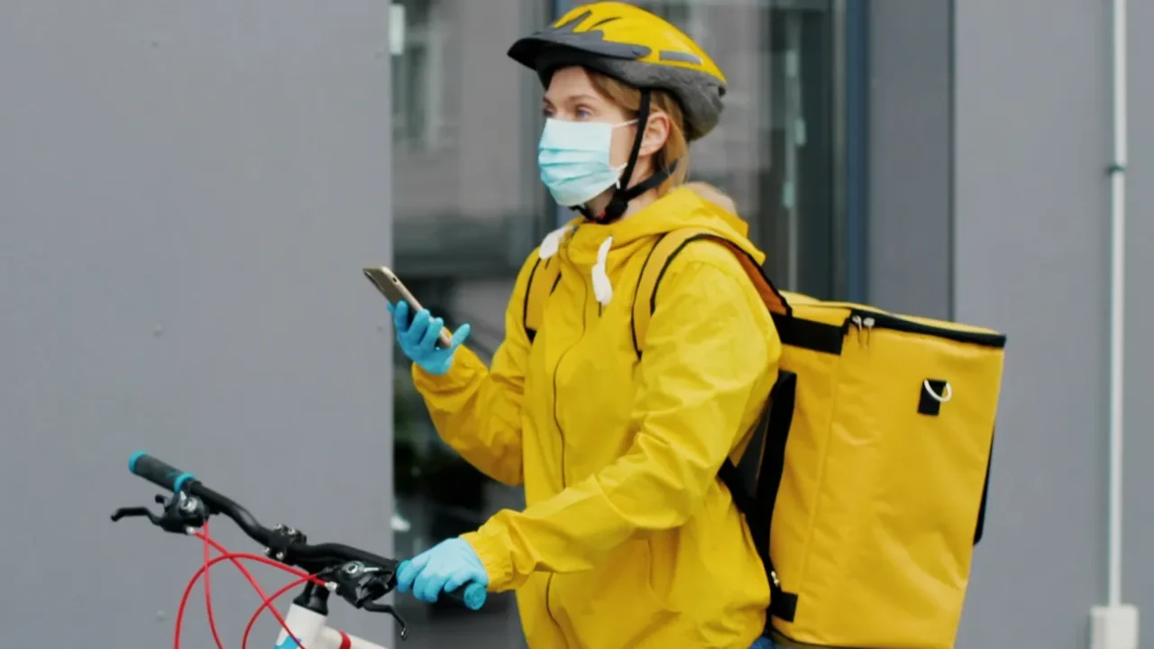 portrait of female courier with a yellow thermal backpack in