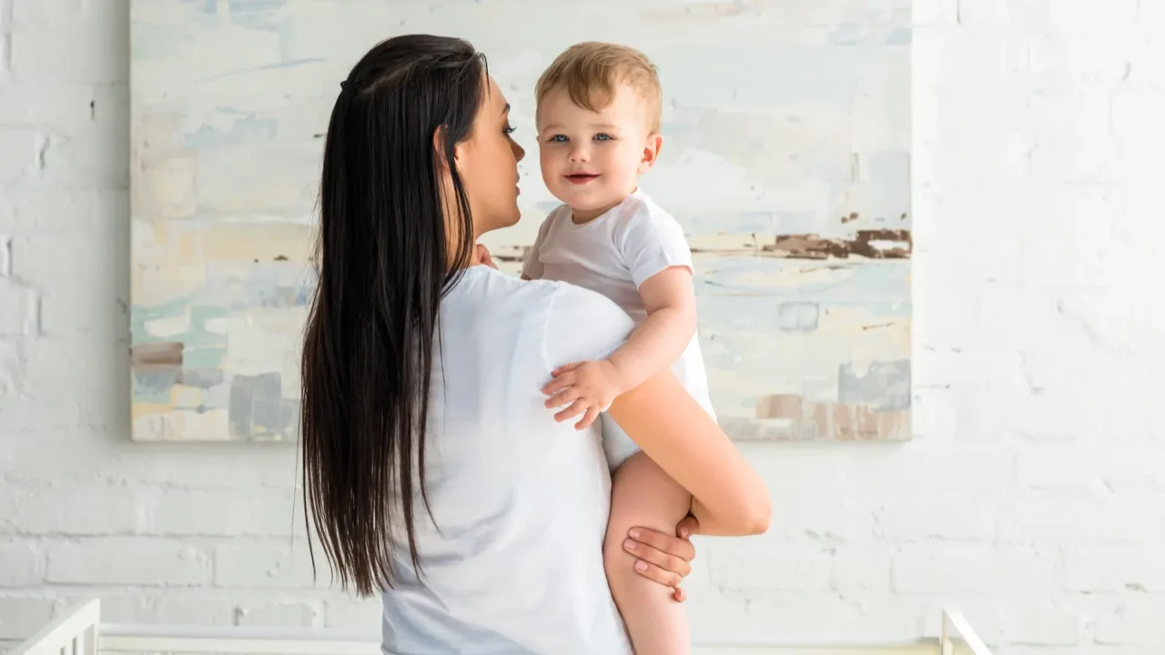 rear view of mother holding cute smiling baby in hands