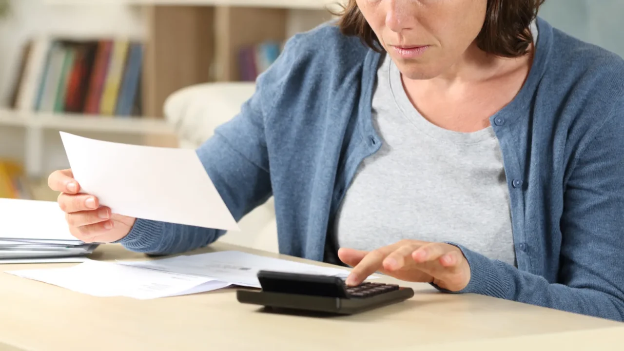 serious adult woman calculating receipts with calculator sitting on