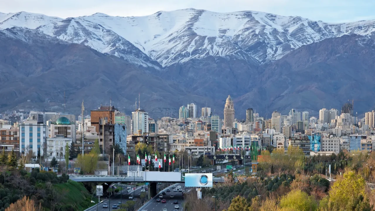 tehran skyline and highway in front of snowy mountains