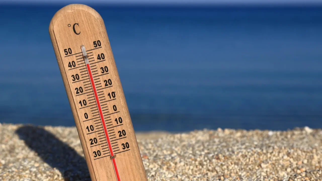 thermometer on a beach shows high temperatures