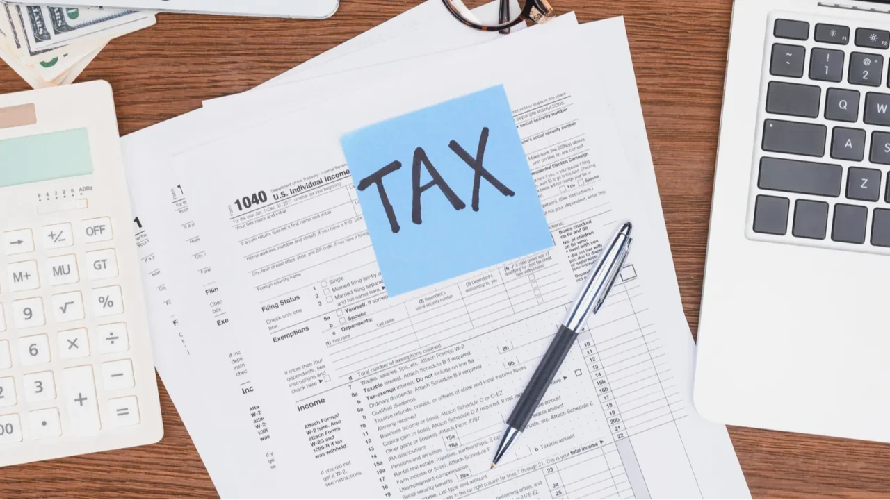 top view of tax forms digital devices and blue card