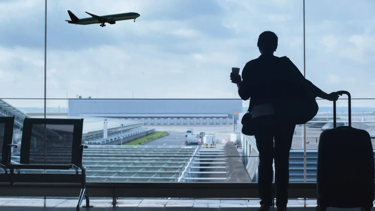 traveler in airport looking at the plane taking off