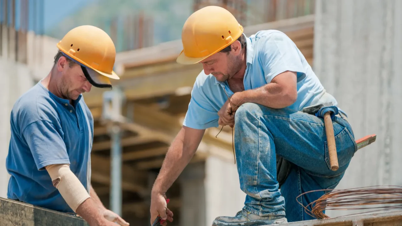 two construction workers installing concrete formwork frames