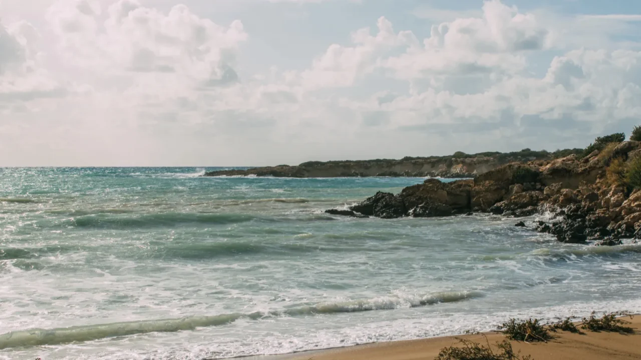 wet and sandy beach near mediterranean sea against blue sky