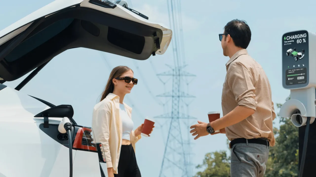 young couple with coffee recharge ev car battery at charging