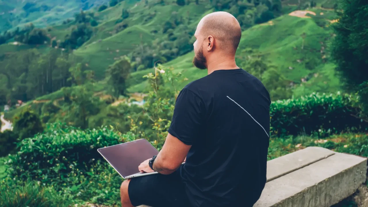 young man freelancer enjoying beautiful green landscapes of high mountains