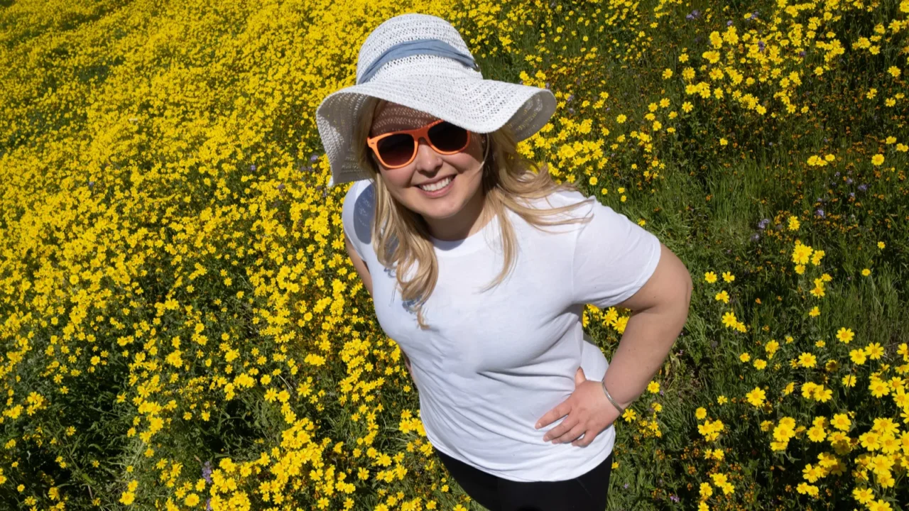 young woman standing in a yellow wildflower field wearing a