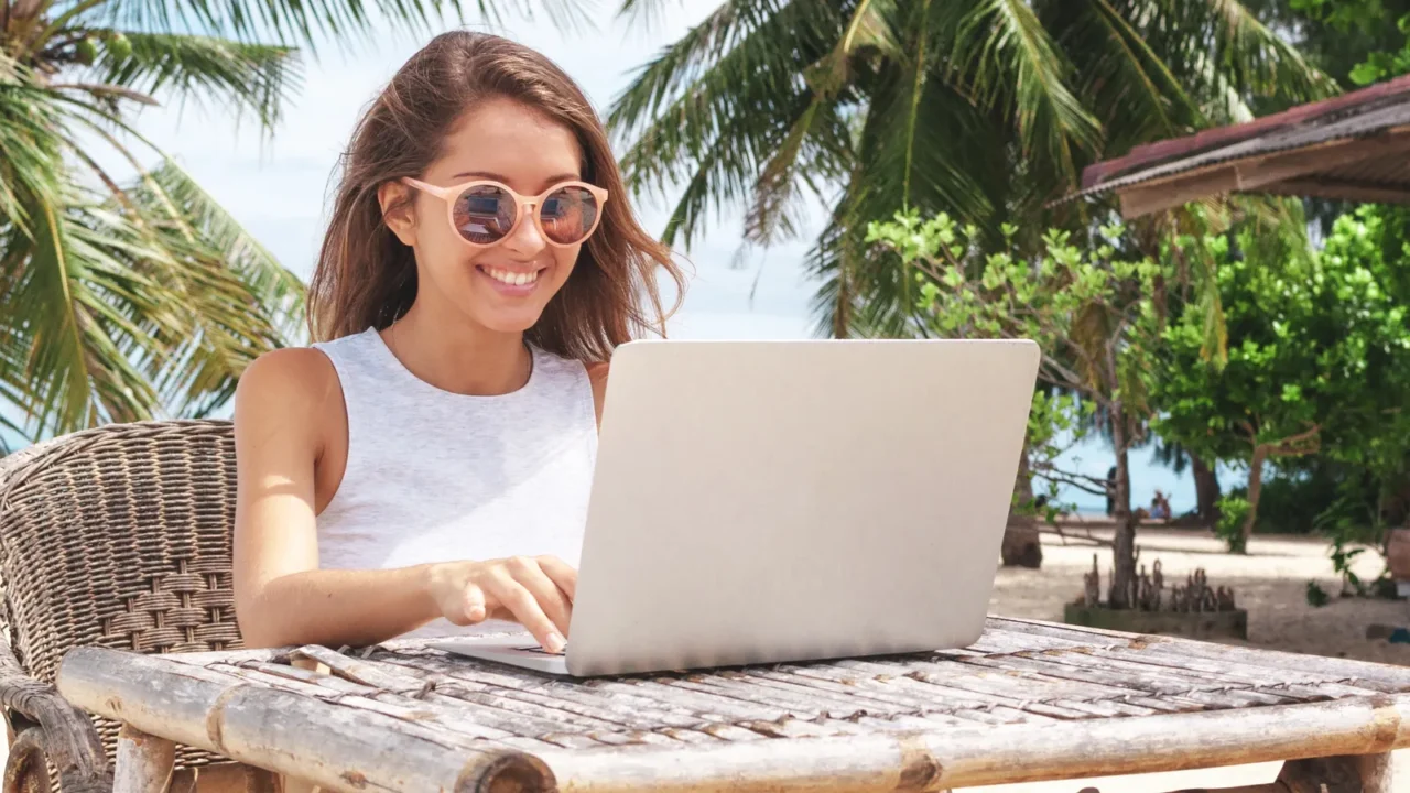 young woman working with laptop computer on tropical island beach