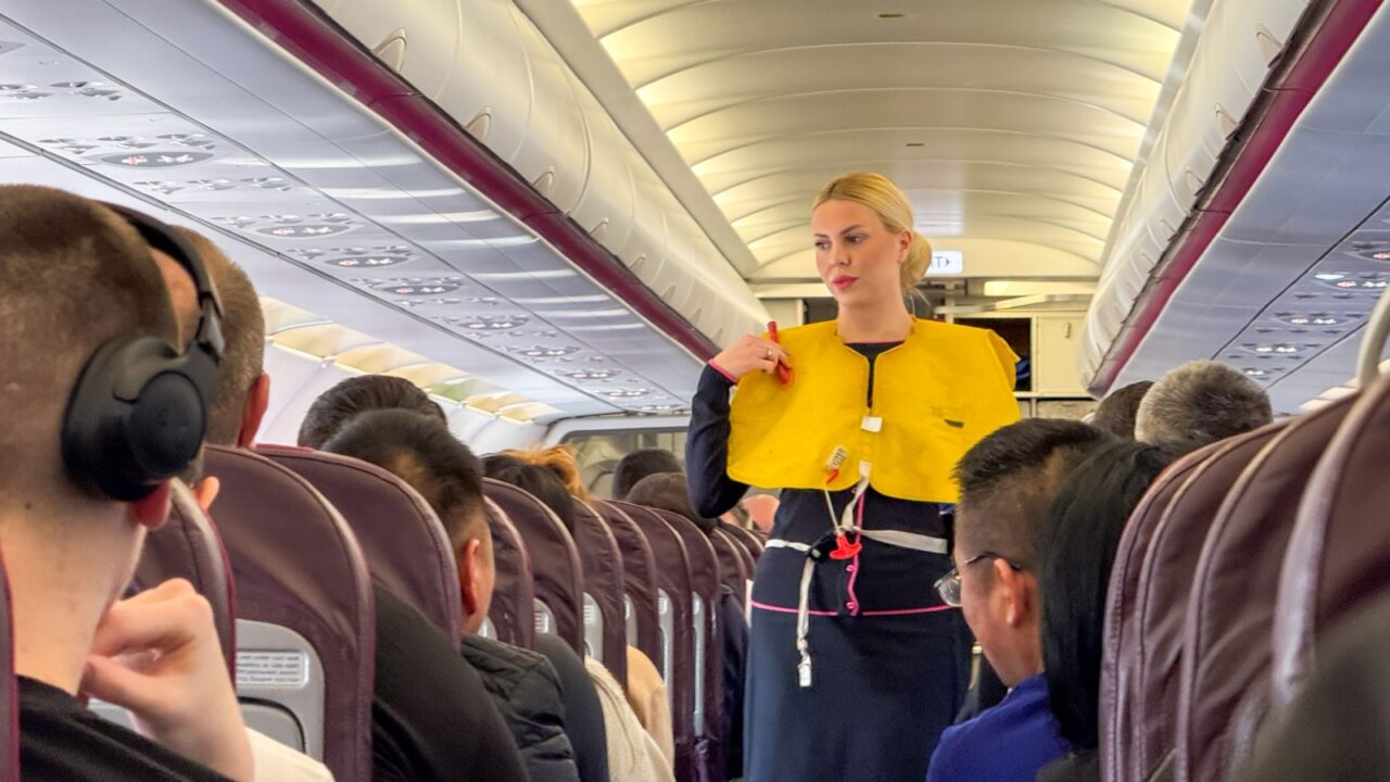 Blonde woman demonstrates safety vest, aviation serenity ritual, World Aviation Day, skyward journey charm April 5 2025, Barcelona, Spain