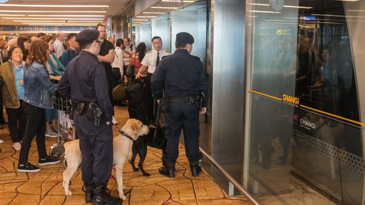 Changi, Singapore - October 17, 2019 : Two policemen with a sniffer dog waiting for the skytrain to arrive at Changi Terminal 2