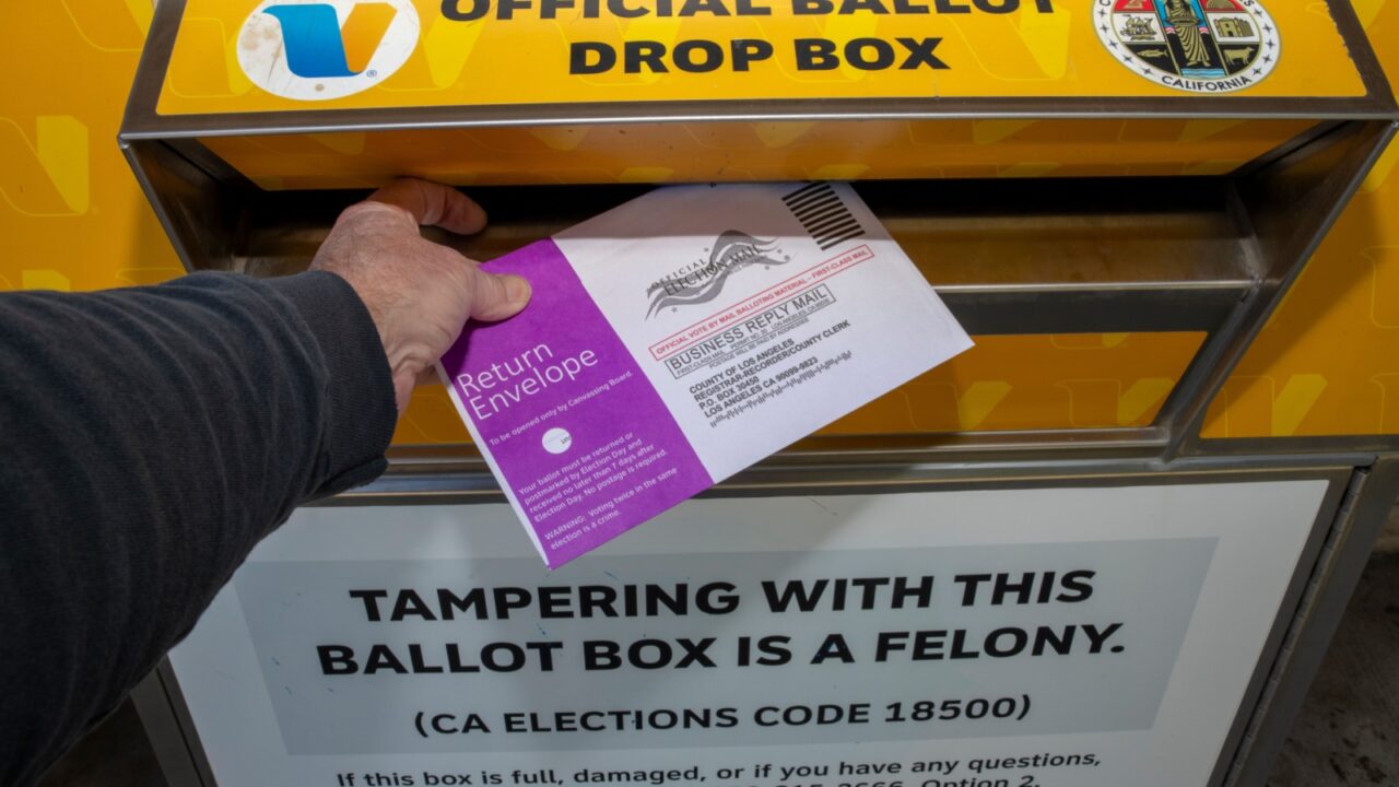 Santa Clarita, Los Angeles County: USA: 2024 March 4: Official Voting Ballot Box outdoors. Man's hand depositing mail in ballot return envelope. Vote by mail. Mail In Ballots, Mail In Voting, Voting by mail.