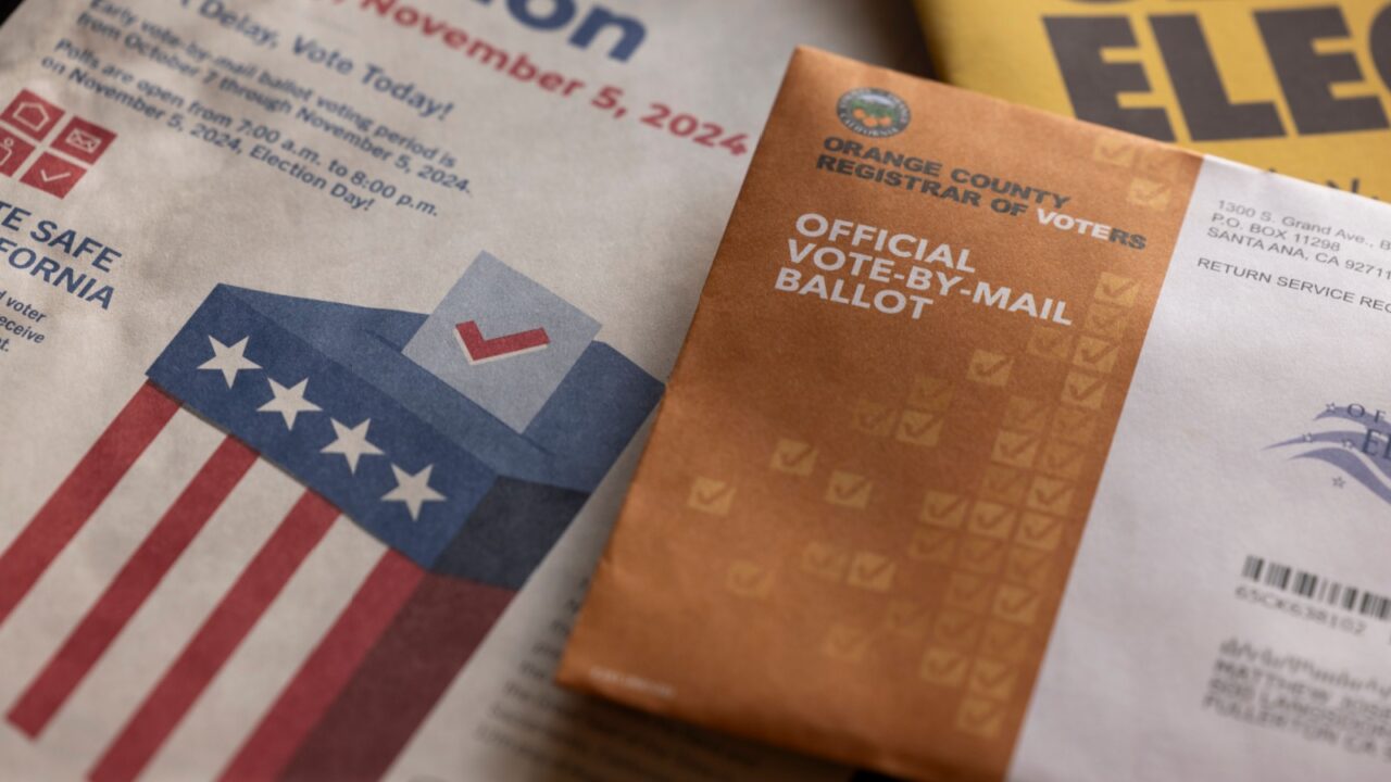 Fullerton, California, USA - October 20, 2024: Afternoon light shines on table of election materials and a vote by mail ballot.