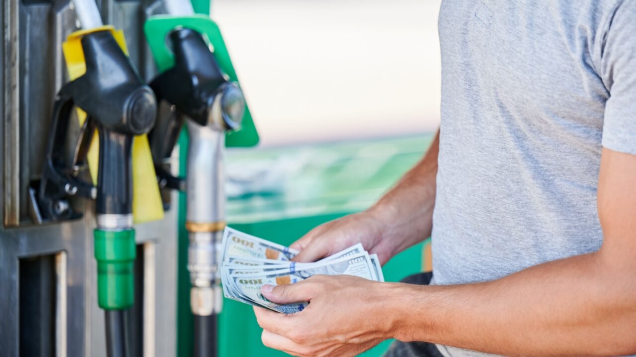 Cropped view of man shocked how much gasoline costs. Driver counting if he has enough money to pay for fuel. Transportation expenses concept.
