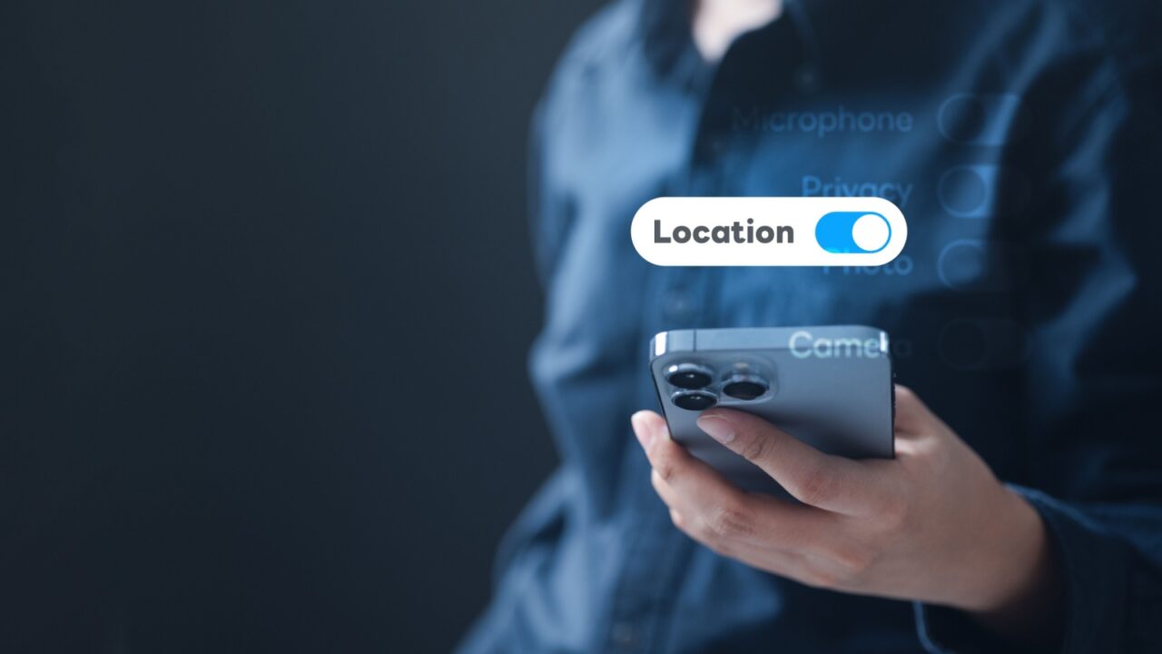 A person holding a smartphone with the location access switch turned on, representing data privacy settings, online security, and digital device protection for safe account management.