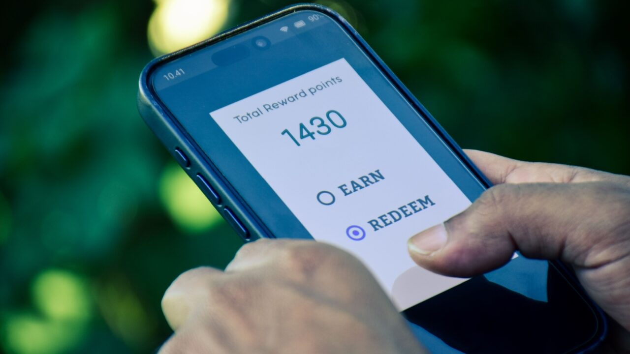 Points and rewards program for online purchase concept. Man chose to redeem points for online shopping. Close up phone screen, outdoor.
