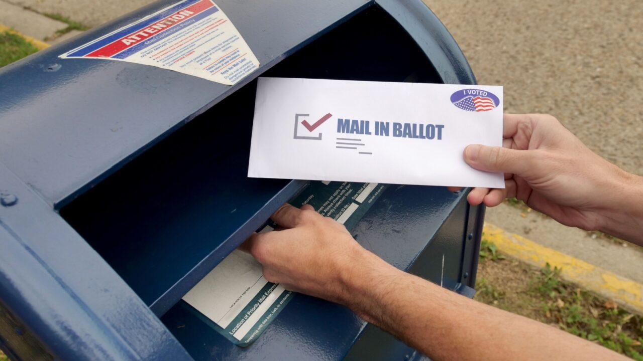 Circa August, 2020 - A man puts an absentee mail-in ballot in the mailbox.