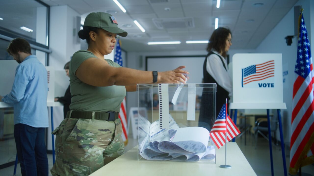 Multiethnic voters or American people vote in booths at polling station. Asian woman and African American female military put bulletins in box. National Election Day in the United States. Civic duty.