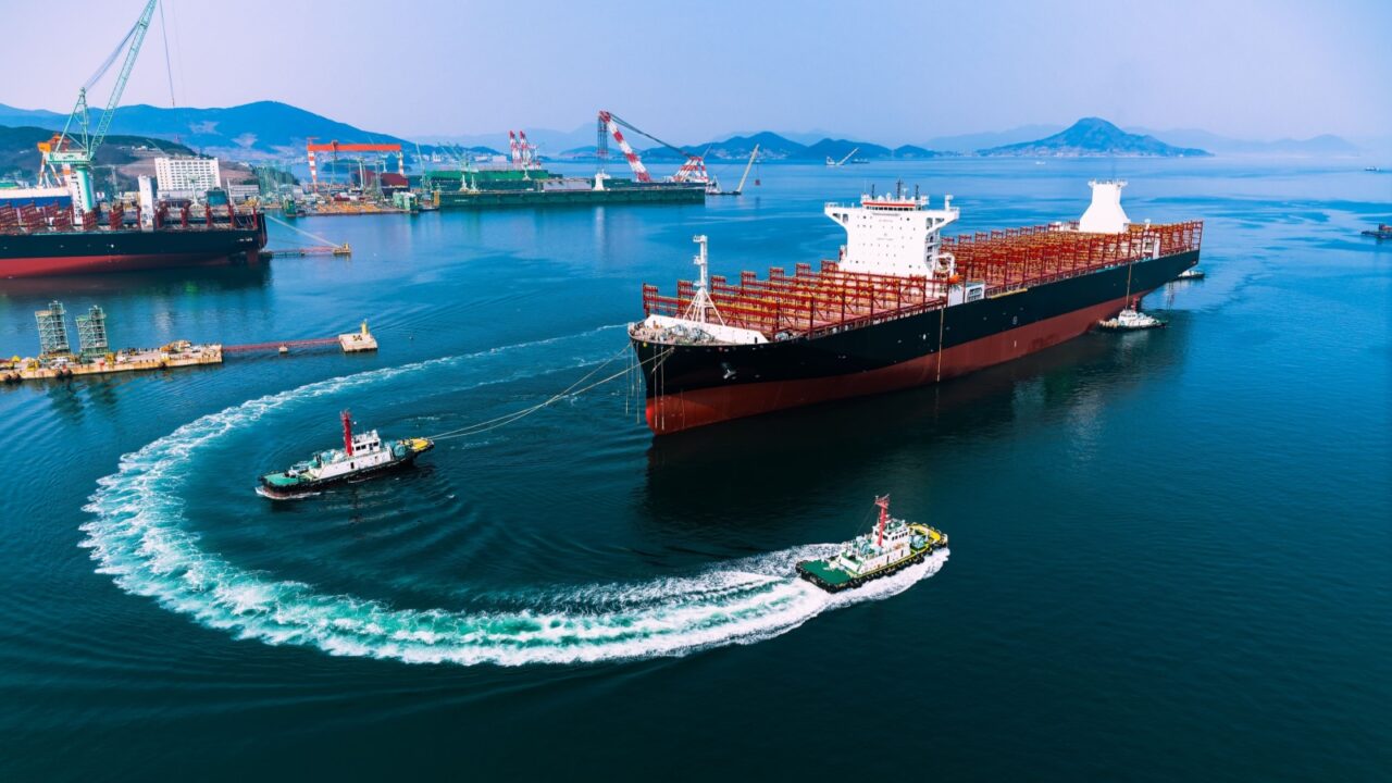 Container ship during port operations with tugs