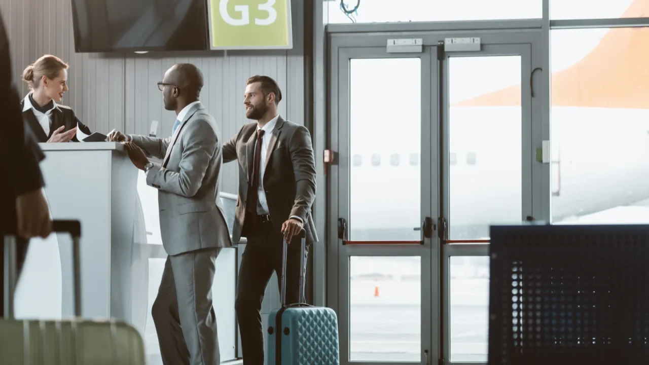 businessmen standing at airport reception to buy tickets while colleague