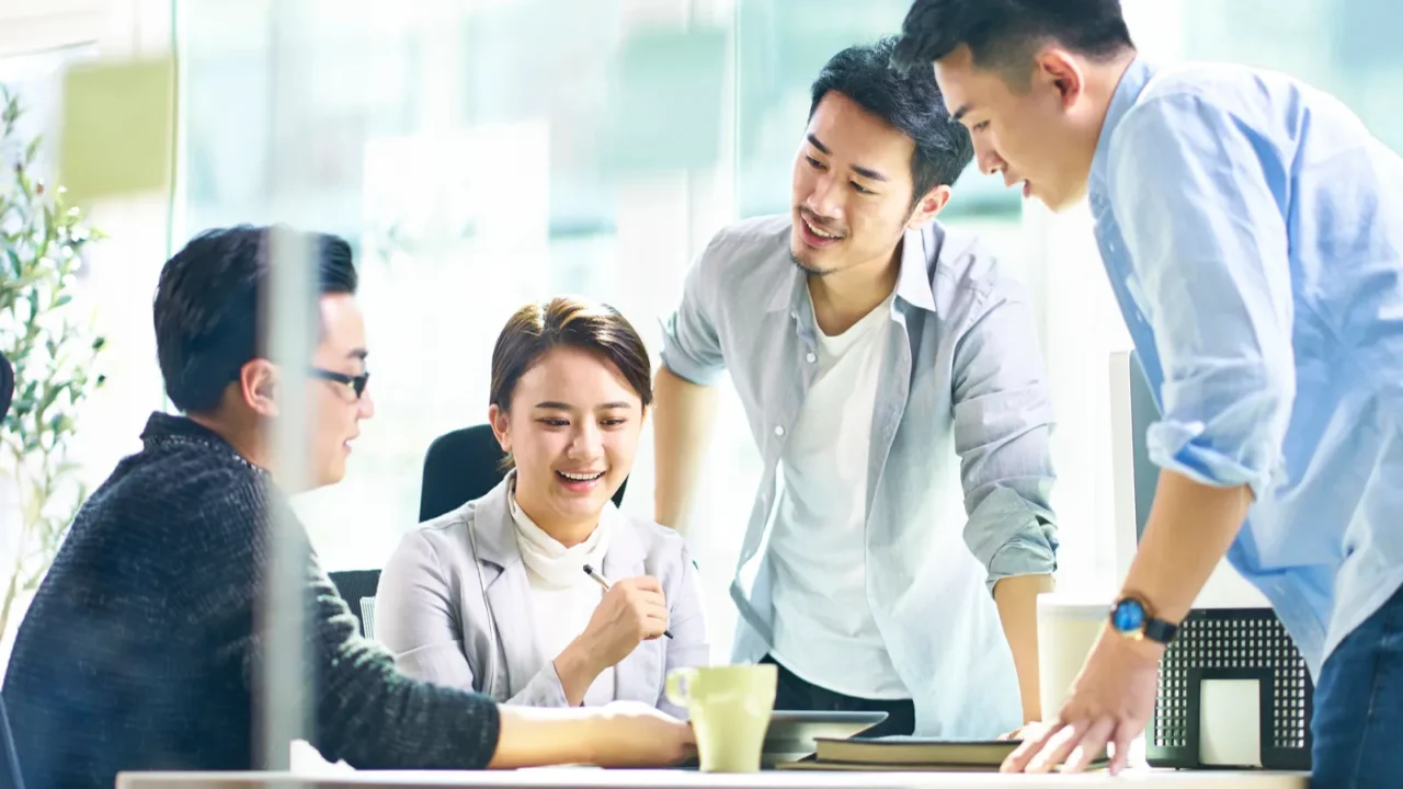 group of four asian teammates working together discussing busine